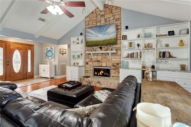 living room featuring a fireplace, ceiling fan, high vaulted ceiling, beamed ceiling, and light hardwood / wood-style floors