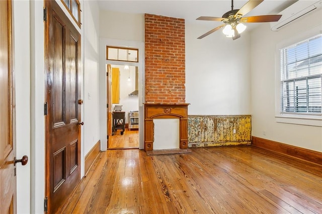 unfurnished living room featuring hardwood / wood-style floors, an AC wall unit, and ceiling fan