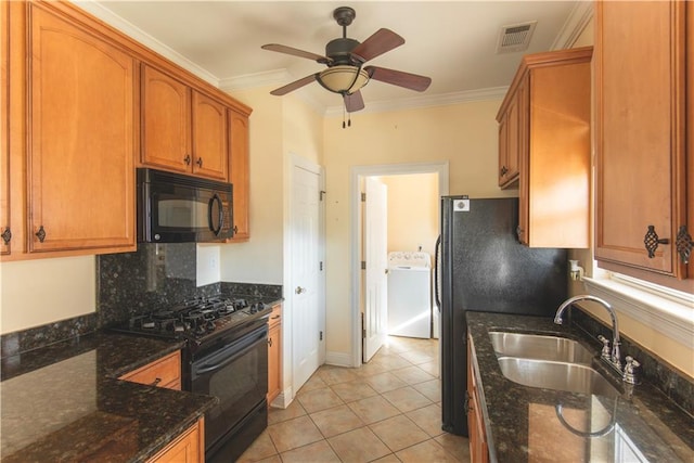 kitchen featuring sink, crown molding, dark stone counters, washer / dryer, and black appliances