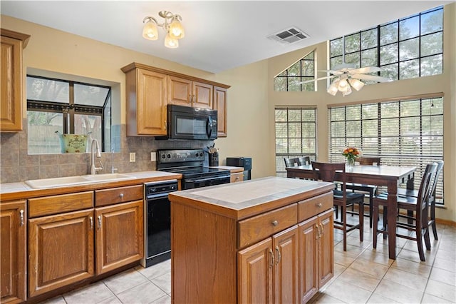 kitchen featuring black appliances, sink, a center island, ceiling fan, and tile counters