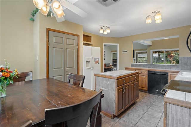 kitchen featuring dishwasher, visible vents, light tile patterned floors, a center island, and white fridge with ice dispenser