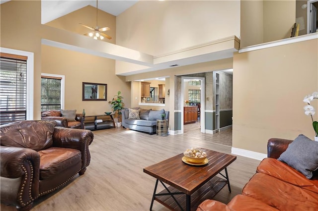 living room featuring light wood-type flooring, a towering ceiling, and ceiling fan