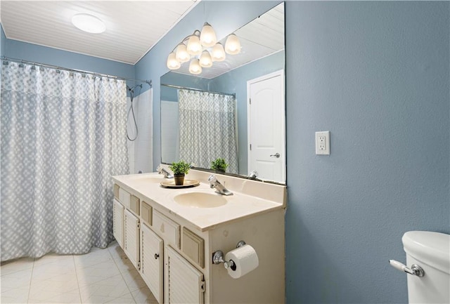 bathroom with a sink, double vanity, toilet, an inviting chandelier, and a textured wall