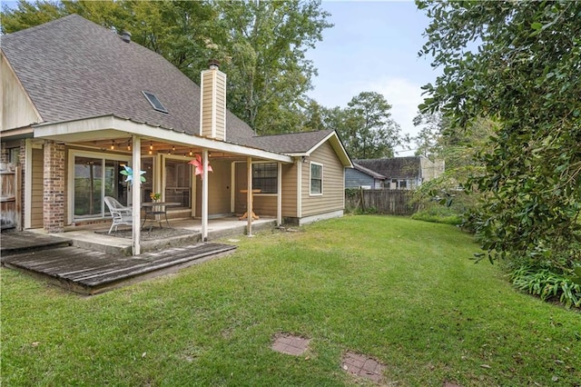 back of property featuring a wooden deck, a yard, and a patio