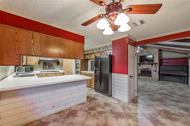 kitchen featuring appliances with stainless steel finishes, sink, kitchen peninsula, beam ceiling, and ornamental molding