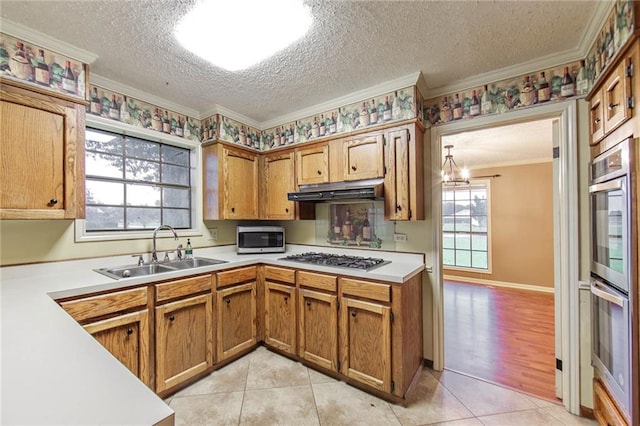 kitchen with light tile patterned floors, a textured ceiling, ornamental molding, sink, and stainless steel appliances