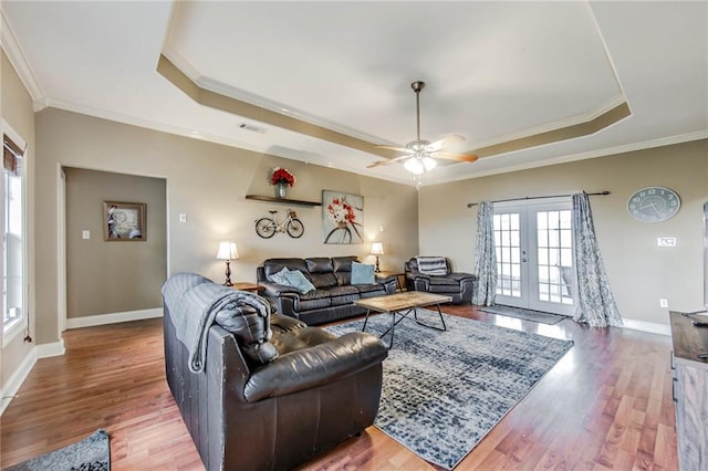 living room with french doors, a tray ceiling, hardwood / wood-style floors, ceiling fan, and crown molding