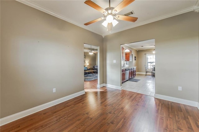 empty room with sink, crown molding, and light wood-type flooring