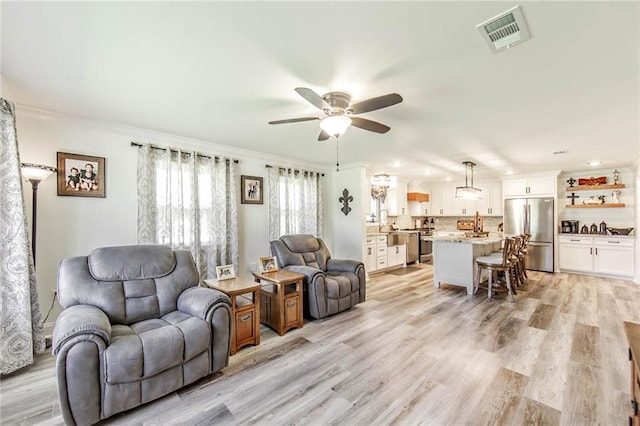 living room with crown molding, light hardwood / wood-style flooring, and ceiling fan