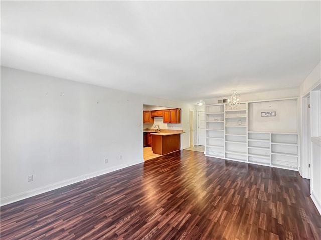 unfurnished living room with a notable chandelier, dark wood-type flooring, and sink