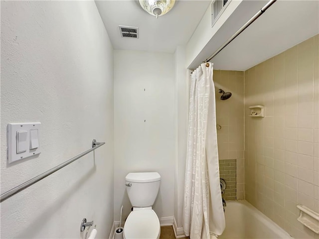 bathroom featuring shower / tub combo and toilet