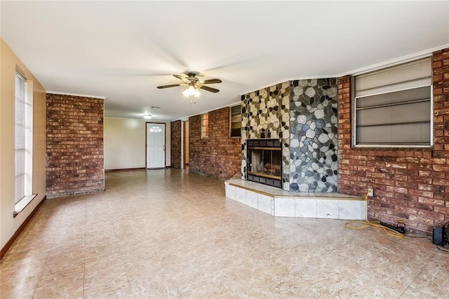 unfurnished living room with brick wall, ceiling fan, a tile fireplace, and a wealth of natural light