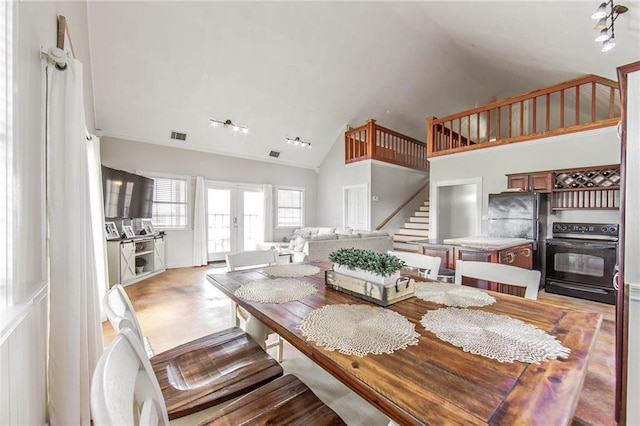 dining area featuring french doors, visible vents, light wood-style flooring, stairway, and high vaulted ceiling