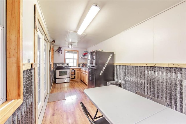 kitchen featuring light countertops, freestanding refrigerator, light brown cabinets, light wood-type flooring, and stainless steel electric range