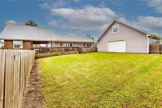 view of yard with a garage, a deck, and an outbuilding