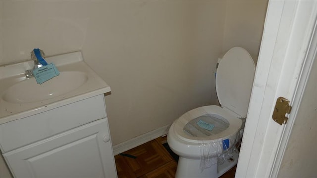 bathroom with vanity, parquet floors, and toilet