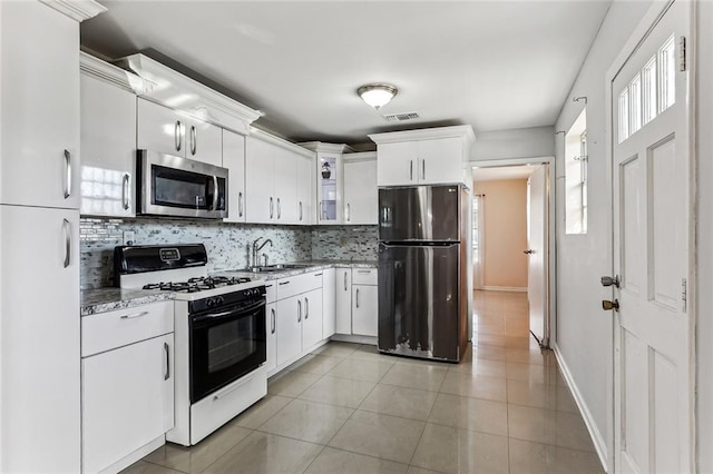 kitchen with sink, white cabinets, light tile patterned flooring, appliances with stainless steel finishes, and tasteful backsplash