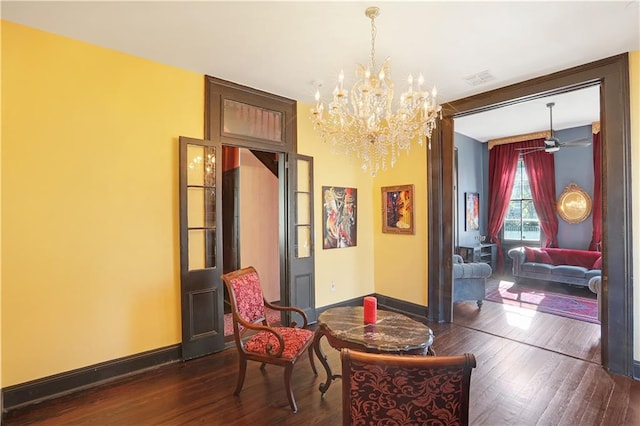 living area featuring dark wood-type flooring and ceiling fan with notable chandelier