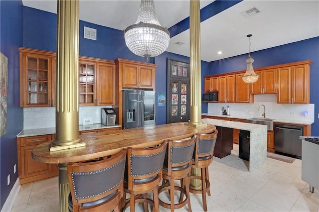 kitchen featuring sink, backsplash, stainless steel appliances, decorative light fixtures, and an inviting chandelier