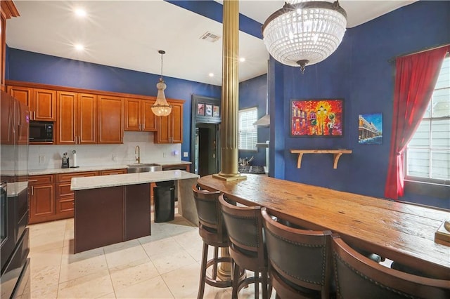 kitchen featuring black microwave, a chandelier, decorative light fixtures, and plenty of natural light