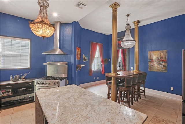 kitchen with a center island, wall chimney exhaust hood, light tile patterned floors, and pendant lighting