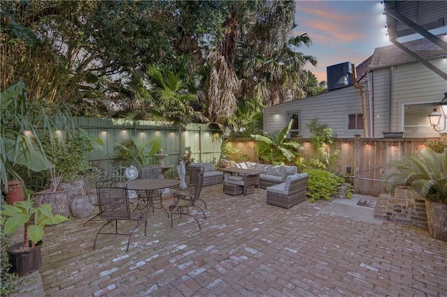 patio terrace at dusk featuring an outdoor living space and central air condition unit