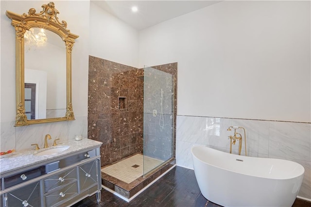 bathroom featuring vanity, hardwood / wood-style flooring, plus walk in shower, and tile walls