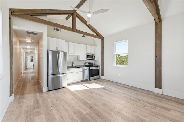 kitchen with appliances with stainless steel finishes, light wood-type flooring, ceiling fan, white cabinets, and high vaulted ceiling