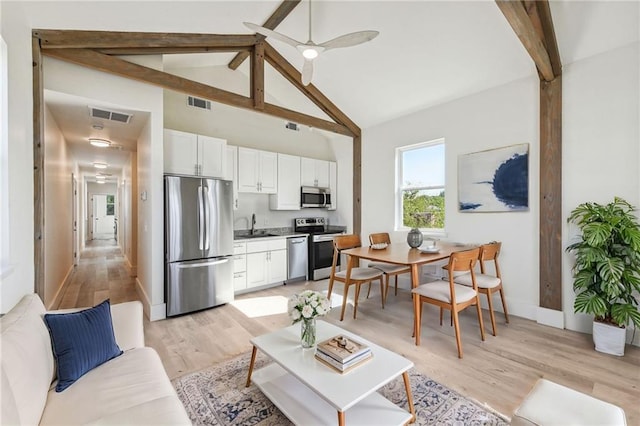 living room with beamed ceiling, sink, light wood-type flooring, high vaulted ceiling, and ceiling fan