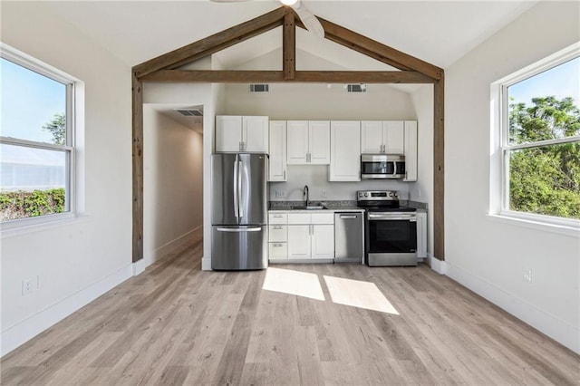 kitchen with a healthy amount of sunlight, stainless steel appliances, and lofted ceiling with beams