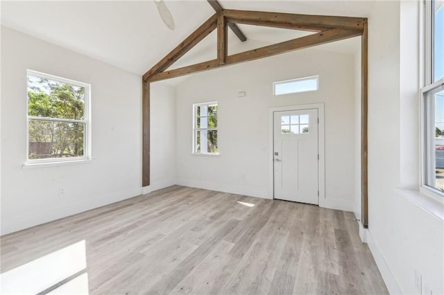 foyer featuring beam ceiling, light hardwood / wood-style floors, high vaulted ceiling, and a healthy amount of sunlight