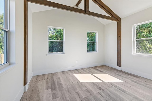 empty room featuring a wealth of natural light and vaulted ceiling with beams