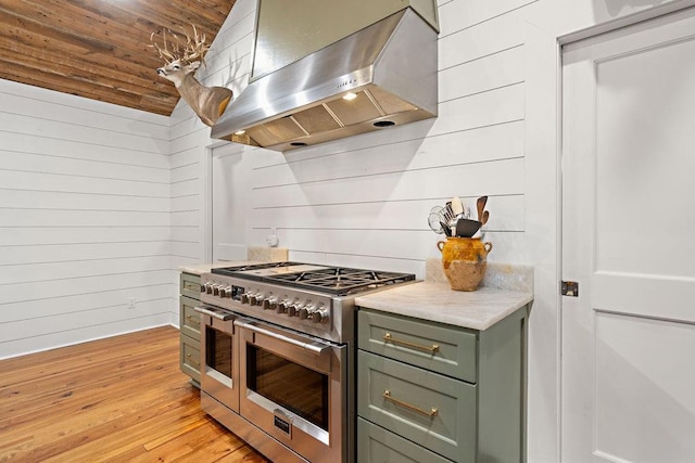 kitchen with wall chimney range hood, wood ceiling, light hardwood / wood-style floors, wooden walls, and double oven range