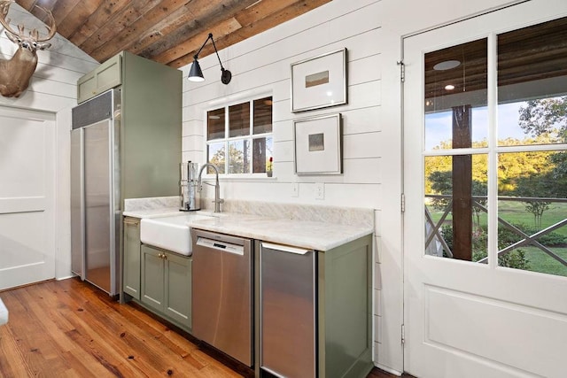 kitchen with lofted ceiling, wood ceiling, appliances with stainless steel finishes, light hardwood / wood-style floors, and sink