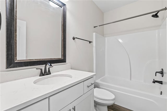 full bathroom with toilet, hardwood / wood-style flooring, vanity, and washtub / shower combination