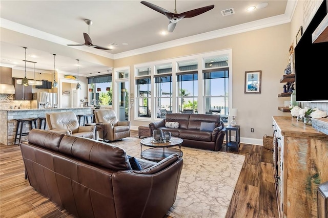 living room with ornamental molding, wood-type flooring, and ceiling fan