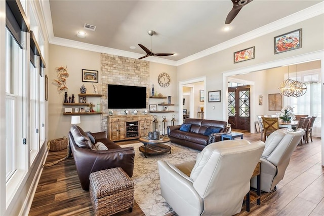 living room with ceiling fan with notable chandelier, a healthy amount of sunlight, ornamental molding, and dark hardwood / wood-style floors