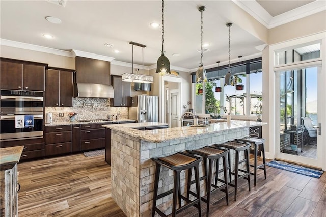 kitchen featuring a large island, stainless steel appliances, dark brown cabinets, and a breakfast bar