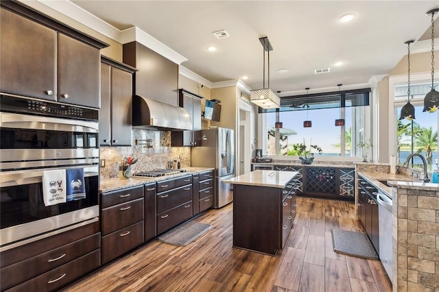 kitchen featuring dark wood-type flooring, stainless steel appliances, a center island, dark brown cabinetry, and pendant lighting