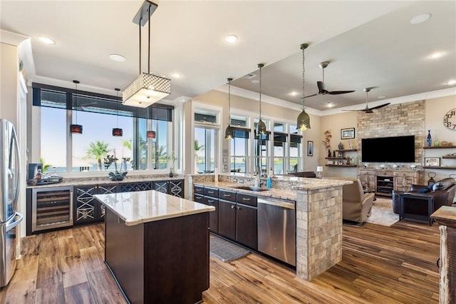 kitchen with appliances with stainless steel finishes, dark brown cabinets, pendant lighting, and a kitchen island