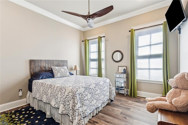 bedroom featuring multiple windows, wood-type flooring, crown molding, and ceiling fan