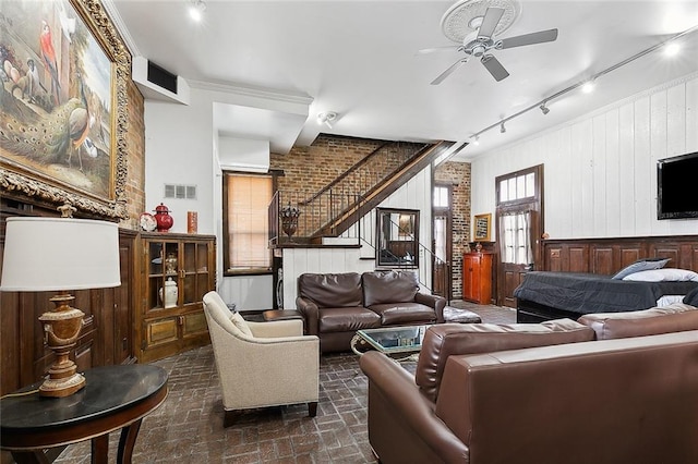 living room featuring wooden walls, track lighting, and ceiling fan