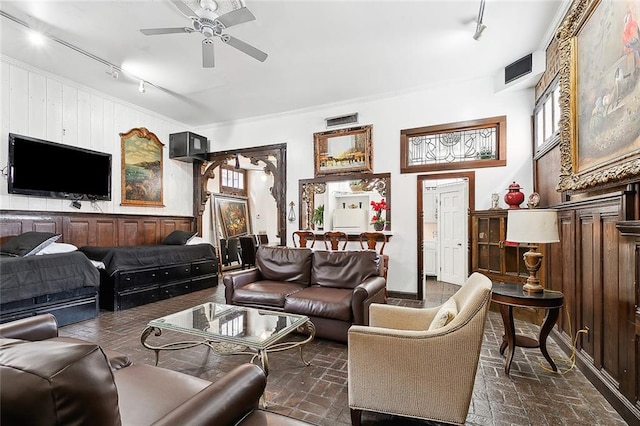 living room with rail lighting, wood walls, and ceiling fan