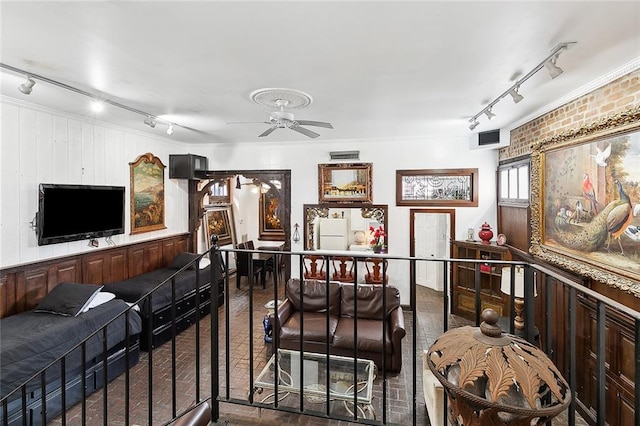 living room featuring wood walls, brick wall, rail lighting, and ceiling fan