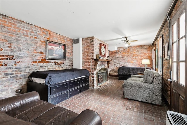 living room featuring brick wall, a fireplace, and ceiling fan