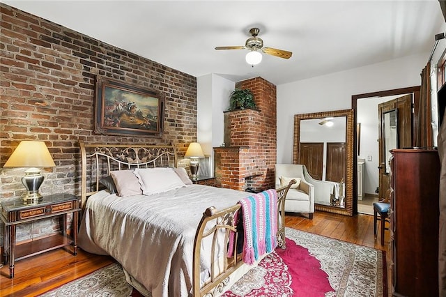 bedroom with brick wall, hardwood / wood-style flooring, and ceiling fan