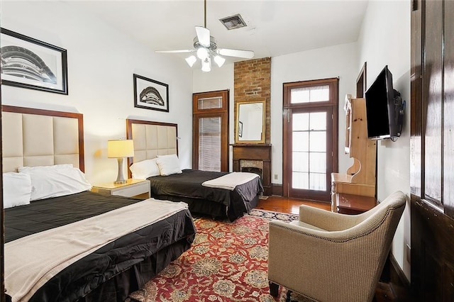 bedroom featuring hardwood / wood-style floors, a brick fireplace, and ceiling fan