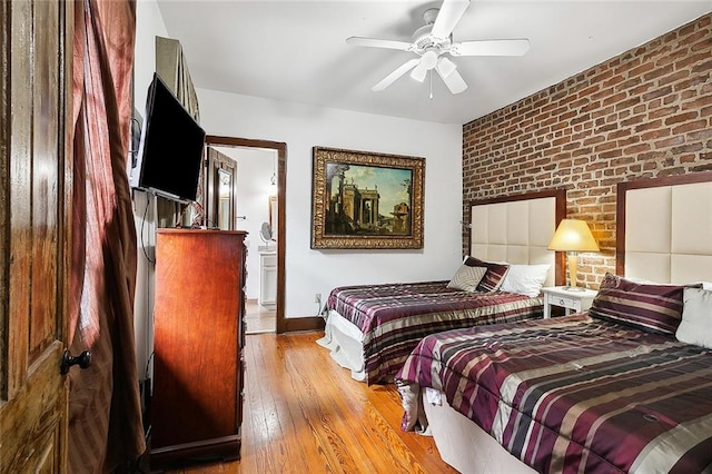 bedroom featuring ceiling fan, brick wall, and light hardwood / wood-style flooring