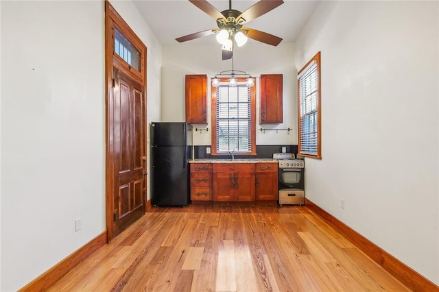 kitchen featuring ceiling fan, stainless steel stove, light wood-type flooring, black refrigerator, and sink