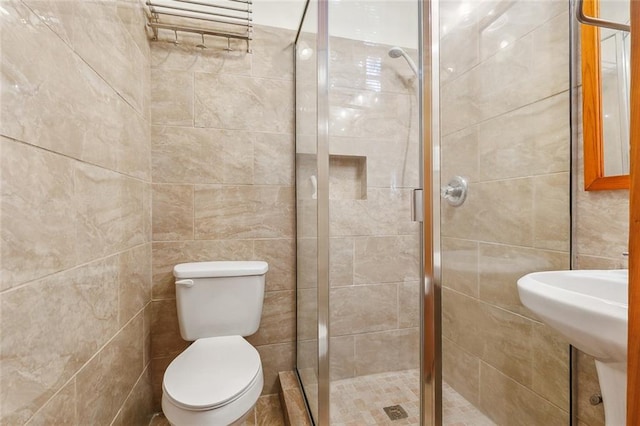 bathroom featuring tile walls, toilet, and an enclosed shower